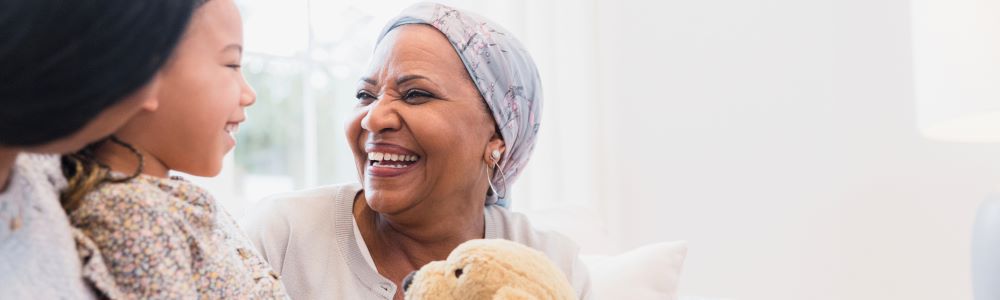 person smiling at their grandchild holding a stuffed animal